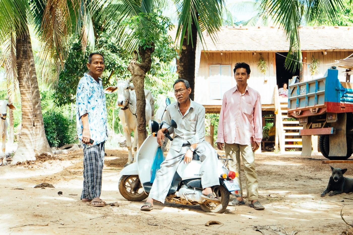 Men chatting beside a scooter on a village street