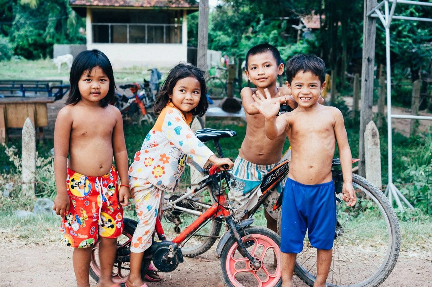 Three kids posing proudly with their bicycle