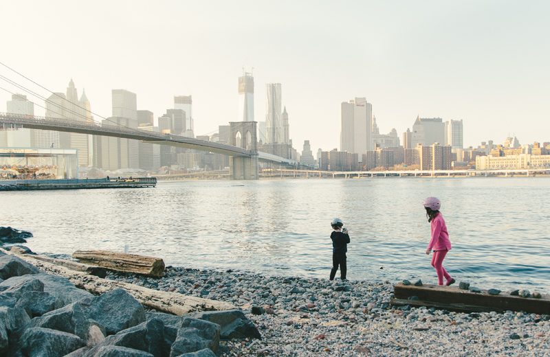 Children by the water beneath the Brooklyn Bridge