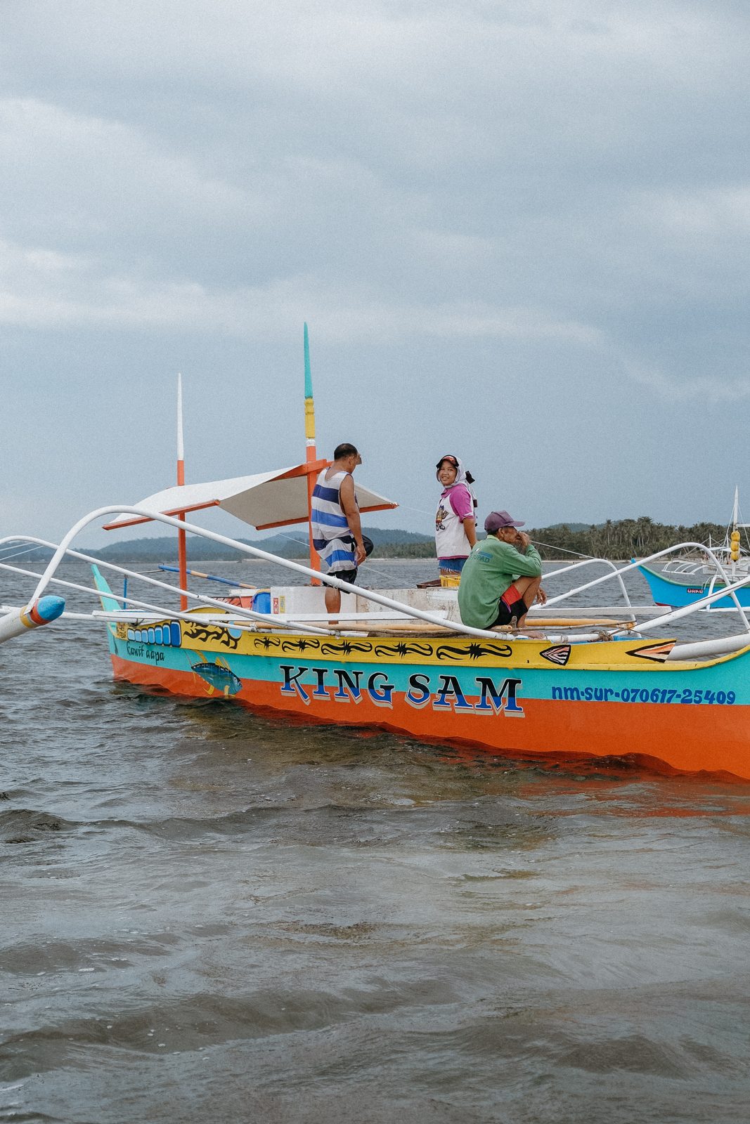 Kids climbing over a wooden outrigger boat