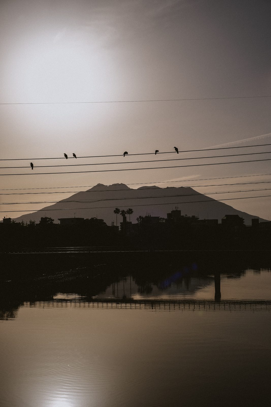 Volcano silhouetted against a dusk sky across the water