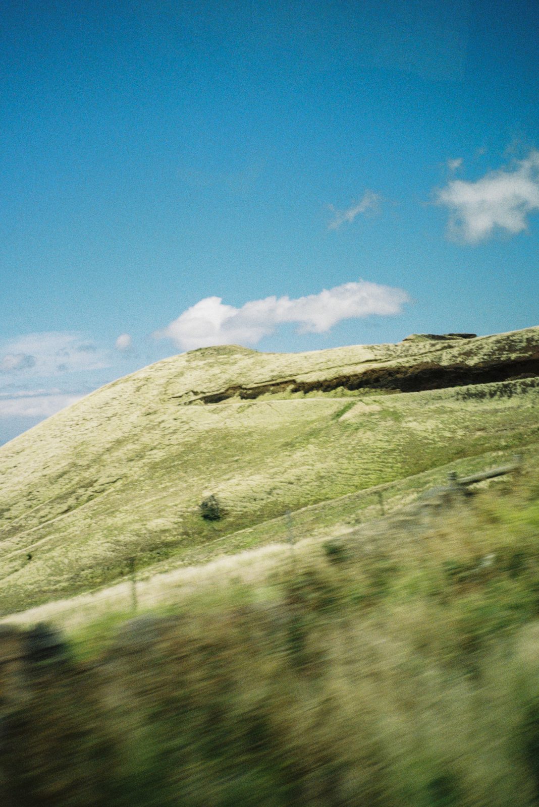 Green hillside rushing past a car window