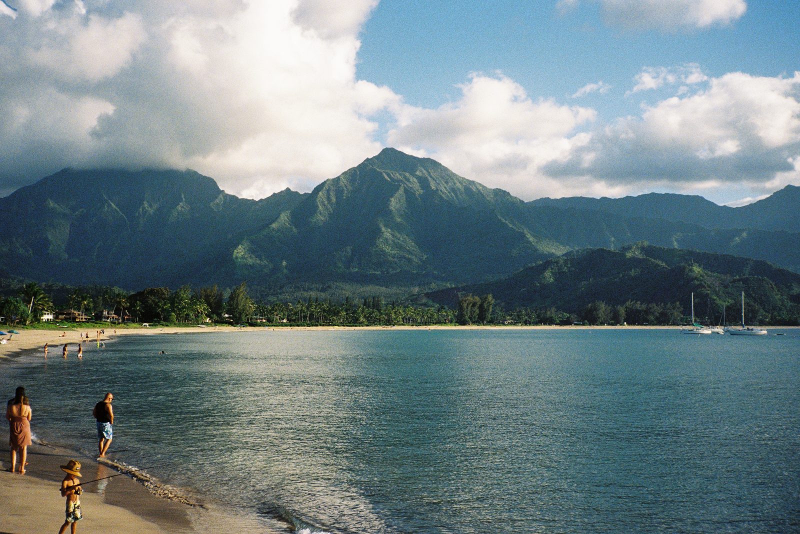 Beachgoers on a bay backed by green mountains
