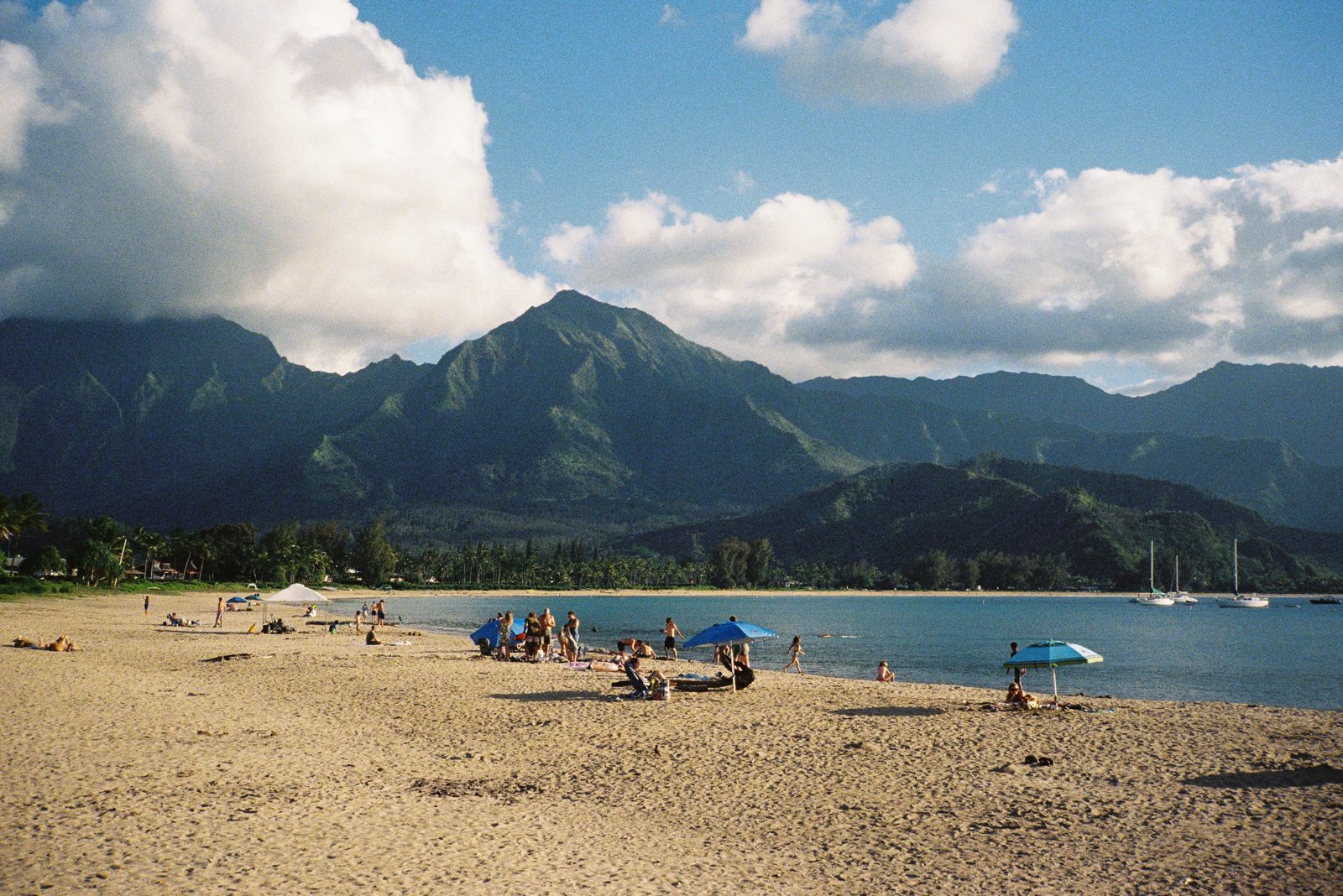 A crowded beach below jagged peaks