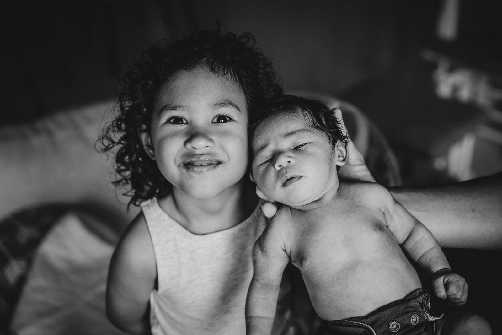 Two siblings cuddling, in black and white
