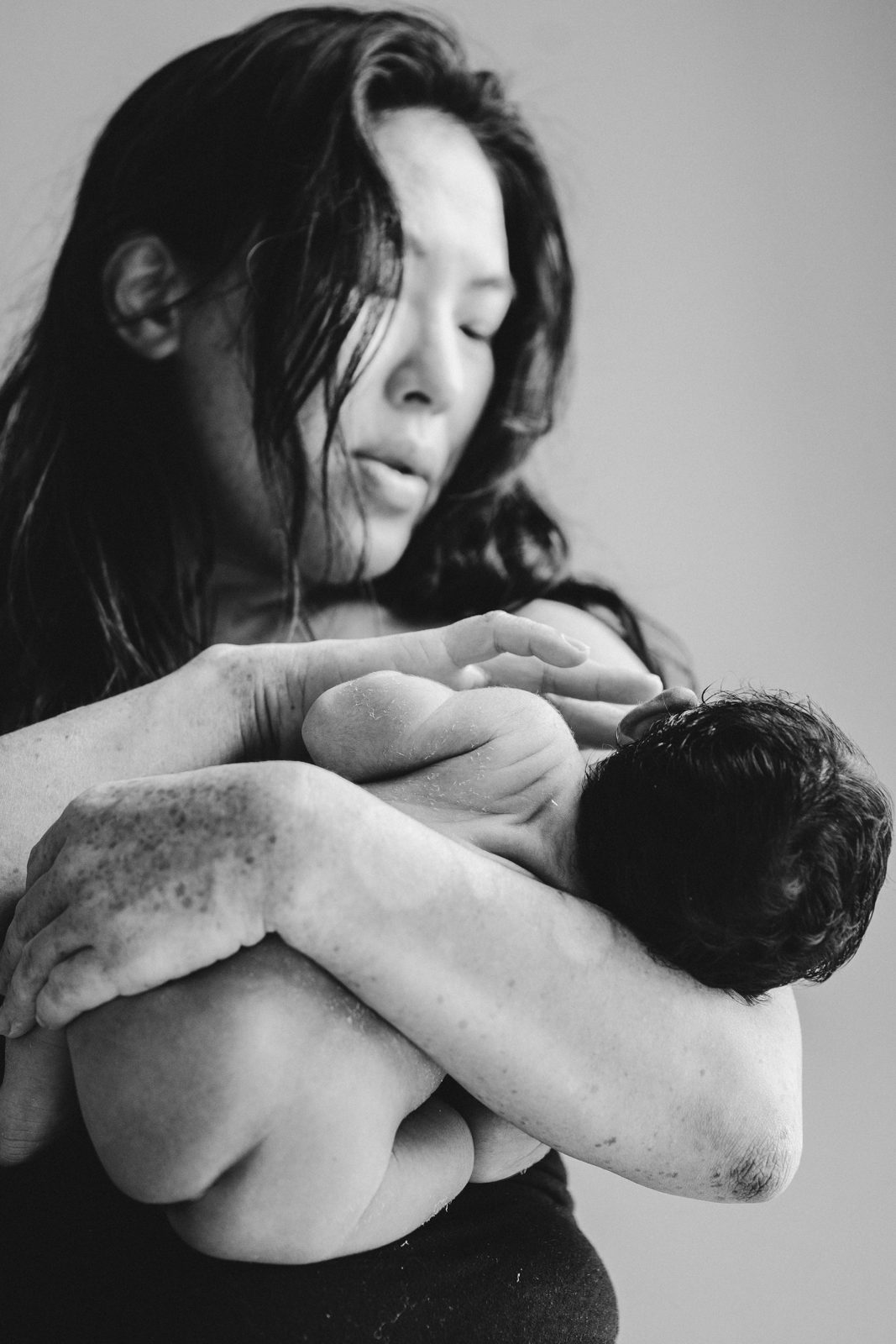 Mother holding her newborn close, in black and white
