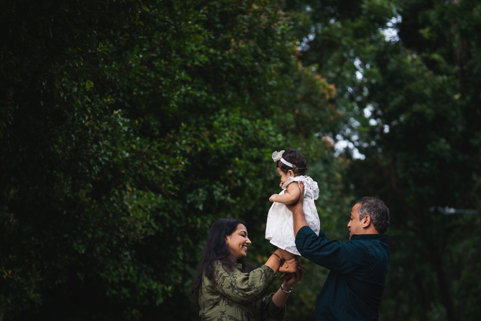 Parents lifting their child among the trees