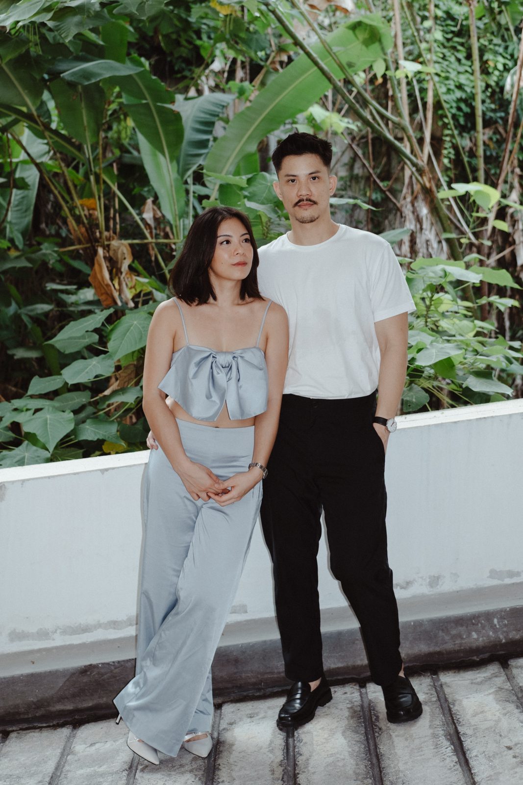 Couple standing in a leafy corner