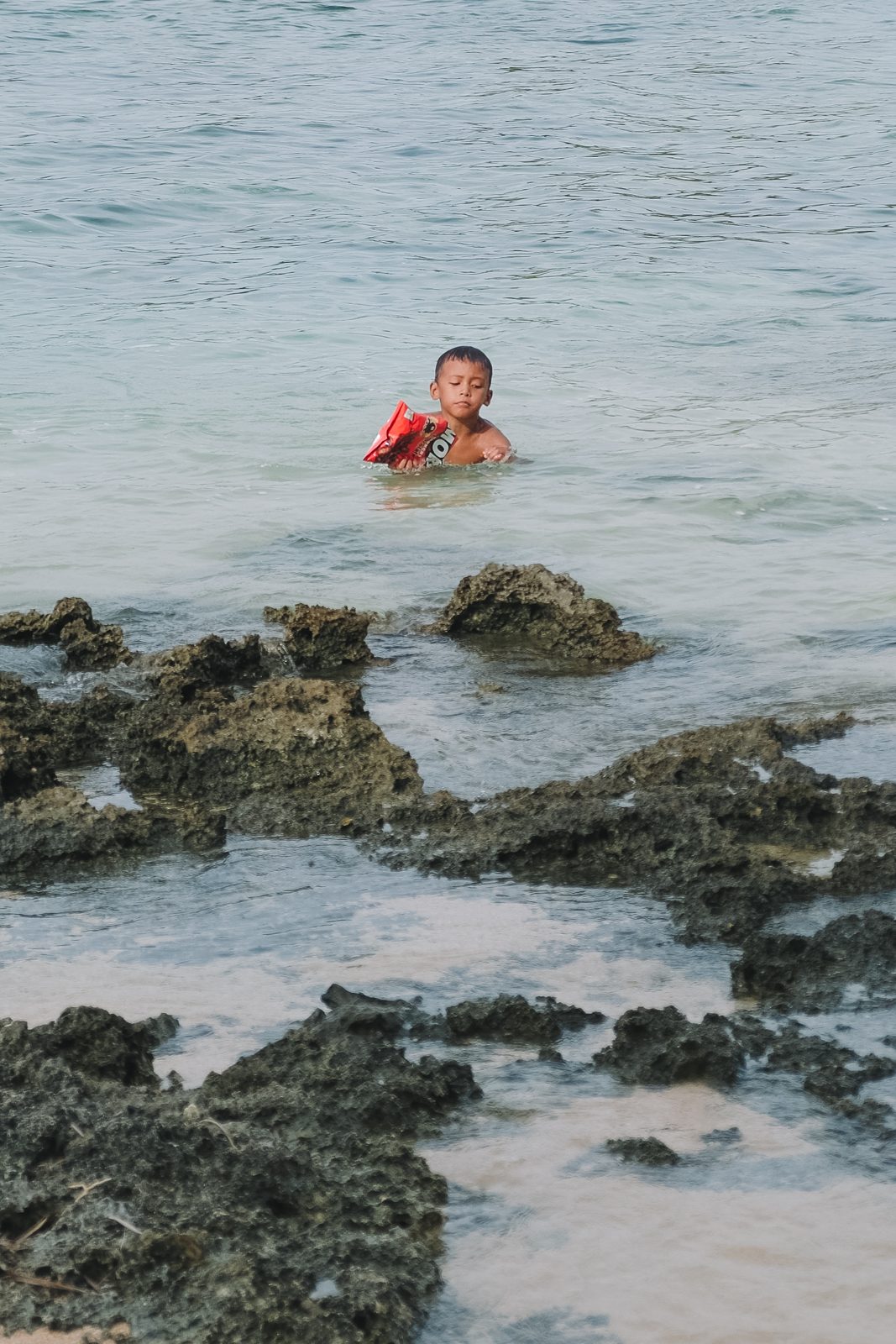 Swimmer among rocks in a turquoise sea